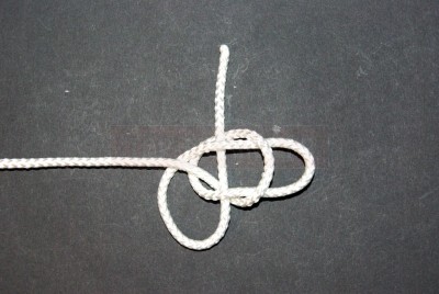 Prenez la deuxième boucle entre le pouce et l\'index de la main droite et faites la passer dans la première. Pendant cette opération, maintenez bien l\'ensemble boucles / brin libre à leur place.