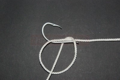 Veillez que le haut de cette boucle repose sur la hampe de l\'hameçon. En la maintenant dans cette position entre le pouce et l\'index, commencez à enrouler le brin libre autour de la hampe en passant dans la boucle.