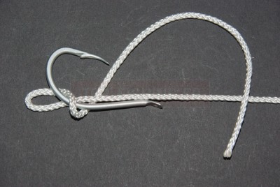 Maintenez un petite boucle tout en tenant la courbure de l\'hameçon entre le pouce et l\'index. Avec le brin libre, passez autour de l\'ensemble ligne mère / hampe. 